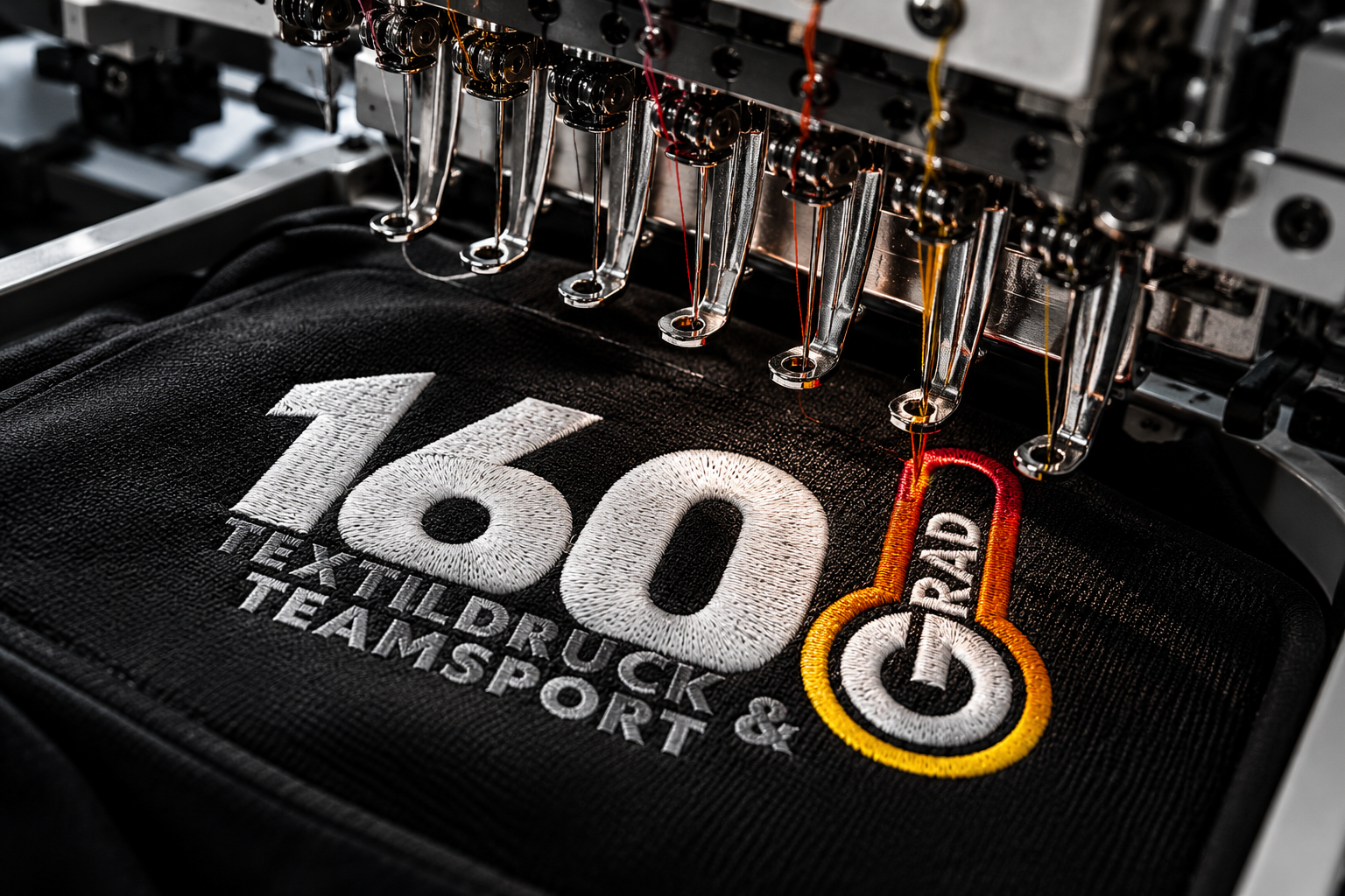 Stickmaschine beim Besticken eines schwarzen Textils mit dem 160-Grad-Logo